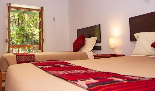 a hotel room with two beds and a window at La Rosa Wellness Lodge in Urubamba