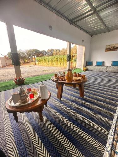a living room with two tables on a carpet at Ferme de luxe in O Ben Slimane
