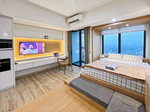 a bedroom with a large bed and a flat screen tv at Stylish Studio SouthGate Apt with Pool, Gym, Netflix by 2ndHome in Jakarta