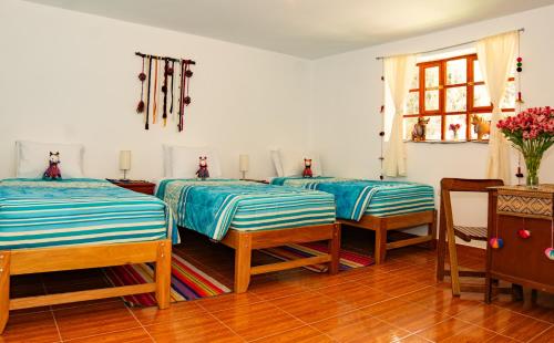 a room with three beds and a table at La Rosa Wellness Lodge in Urubamba