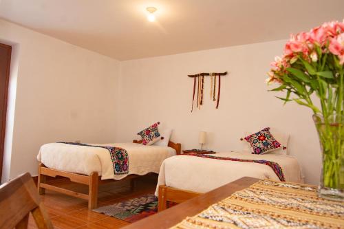 a room with two beds and a vase of flowers at La Rosa Wellness Lodge in Urubamba