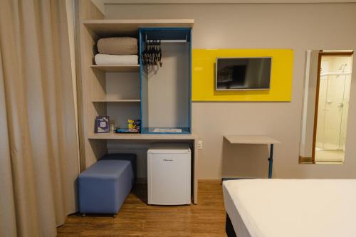 a room with a bed and a shelf with towels at Hotel Caiuá Lago Umuarama in Umuarama