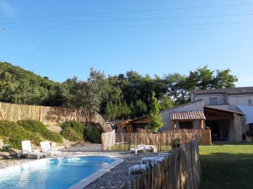 une cour avec une piscine entourée de chaises et une clôture dans l'établissement Gîte de Pied Chapel - Piscine, spa et pleine nature, à Alba-la-Romaine