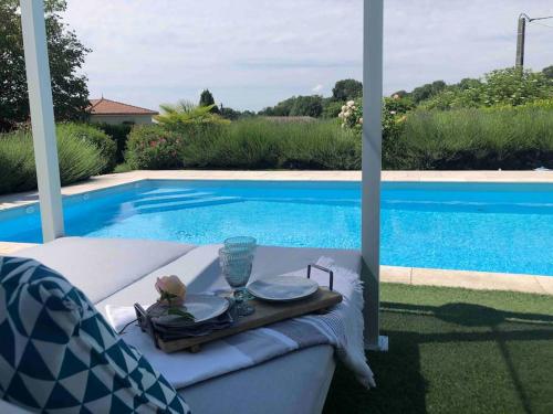 a table with a tray next to a swimming pool at Le gîte de Lou - Piscine privative et massages Bien-être in Mazerolles