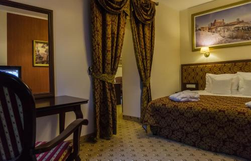 a hotel room with a bed and a desk and a mirror at Zamek Gniew - Pałac Marysieńki in Gniew