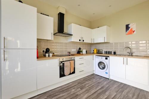 a kitchen with white cabinets and a washer and dryer at Large 2-3 Bed FREE Parking, En-suite in Harrogate