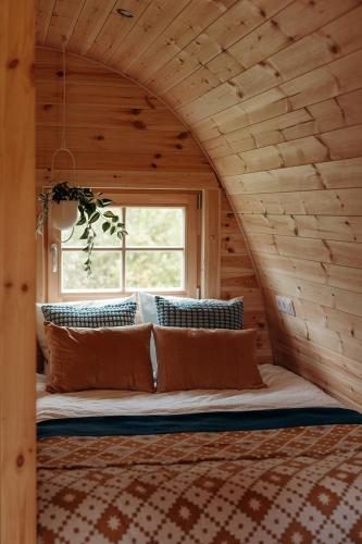a bed in a log cabin with a window at Parcpod Kapèlkeshof in Grashoek