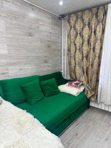 a green couch in a room with a window at Можно оплатить картой in Chişinău