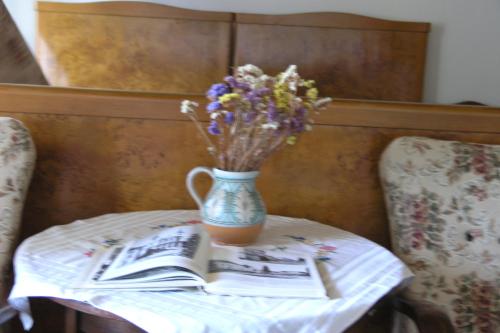 a vase of flowers sitting on a table with a book at Faluszéli Vendégház - Boncz Porta in Nagyrákos
