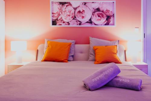 a bedroom with a bed with purple and orange pillows at AppartSpa59 - Suite Tentation - Balnéo, Sauna - Secret Room en option supplémentaire in Valenciennes