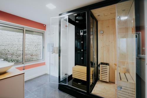 a bathroom with a glass shower with a sink at AppartSpa59 - Suite Tentation - Balnéo, Sauna - Secret Room en option supplémentaire in Valenciennes