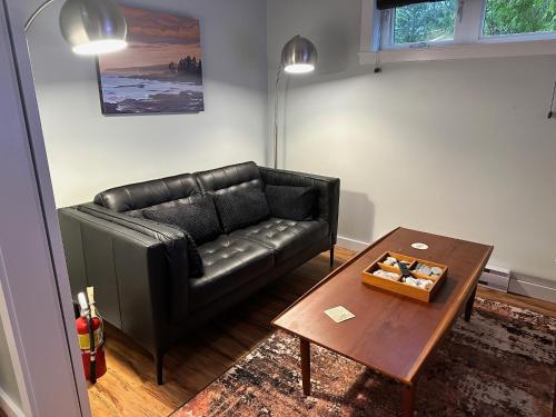 a living room with a black leather couch and a table at Eagle Way in Port Renfrew