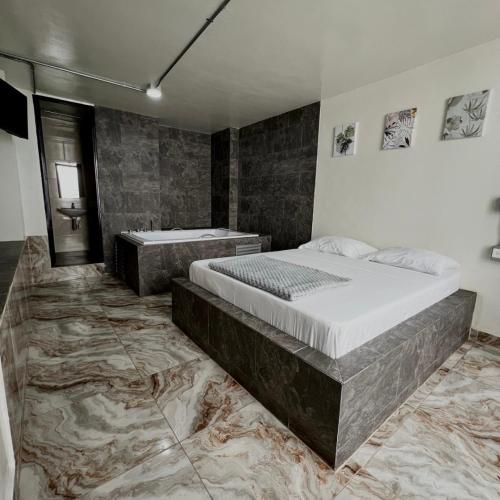 a bedroom with a large bed and a tub at Hotel Villa Nueva Comfort in Medellín