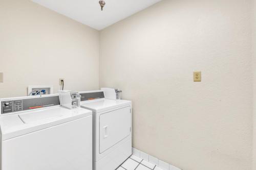 a white laundry room with a washer and dryer at City Centre Inn at Newport News in Newport News