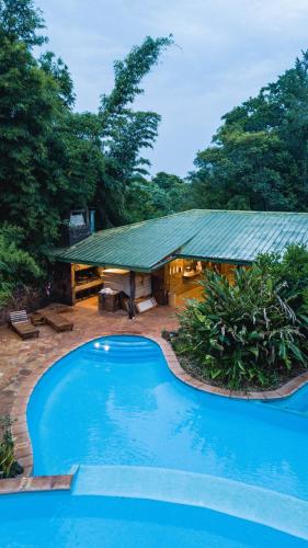 a blue swimming pool in front of a house at La Aldea De La Selva Lodge in Puerto Iguazú