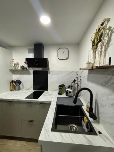 une cuisine avec un évier et une horloge murale dans l'établissement Appartement paisible, à Argenteuil