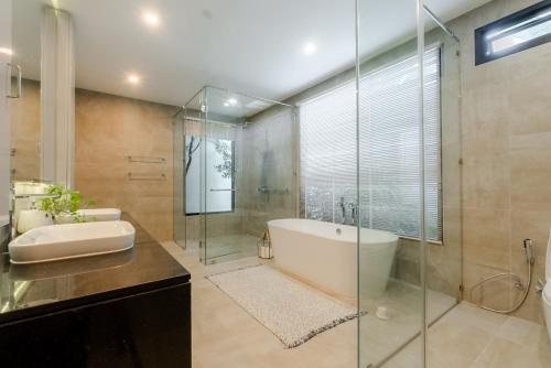 une salle de bain avec baignoire et douche en verre dans l'établissement Fully renovated Pool Villa 4BR Bangtao and Layan Beach in Cheong Thalea, Phuket, à Phuket