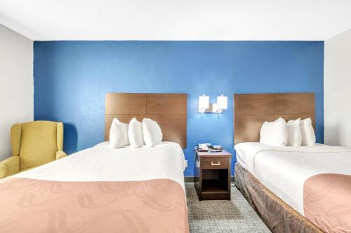 a hotel room with two beds and a chair at City Centre Inn at Newport News in Newport News