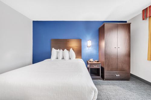 a bedroom with a large bed and a wooden cabinet at City Centre Inn at Newport News in Newport News