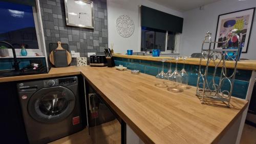 a kitchen with a wooden counter with a washing machine at 175 On Clyde - Spacious & Cosy Cedar Wood Bungalow in Helensburgh