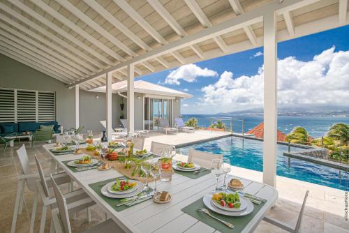 a dining room with a table and a view of the ocean at Villas Tangarane in Les Trois-Îlets