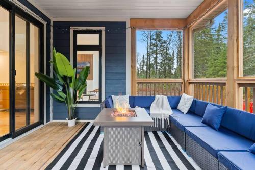 a blue couch on a screened porch with a fireplace at Celestial Cottage with HotTub, Cold Plunge,Games in Dwight