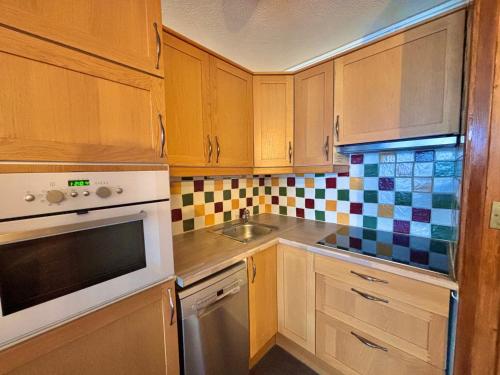 une cuisine avec des armoires en bois et un évier dans l'établissement Appartement rénové pour 4 pers au pied des pistes - La Croisette - FR-1-452-196, aux Menuires