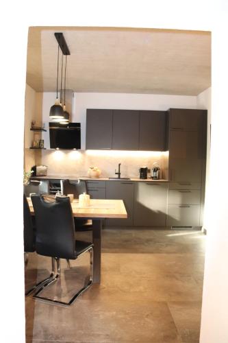 a kitchen with a wooden table and black cabinets at Appartements Marktplatzerl in Mauterndorf