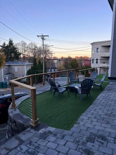 a patio with chairs and a table on the grass at Modern 3BR Near FSU - 15 Min to Wachusett in Fitchburg