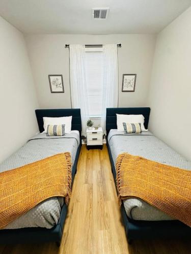 two twin beds in a room with a window at Modern 3BR Near FSU - 15 Min to Wachusett in Fitchburg