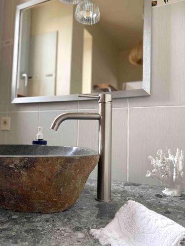 une salle de bain avec un lavabo en pierre et un miroir dans l'établissement Le Moulin Du Port, à Saint-Georges-sur-Cher