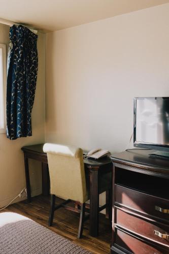 a room with a desk with a television and a chair at La Hacienda Motel in Seattle