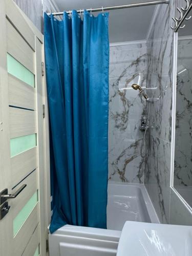 La salle de bains est pourvue d'un rideau de douche bleu à côté d'une baignoire. dans l'établissement Cozy good apartment, à Chişinău