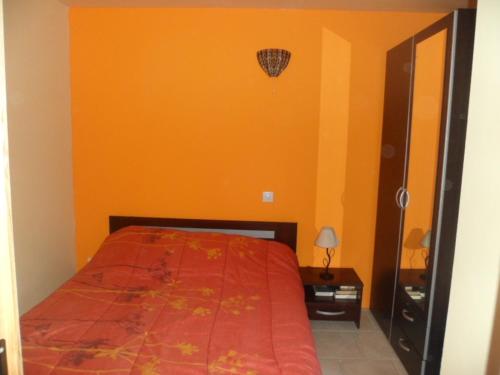 une chambre avec un lit avec un mur orange dans l'établissement La Maison au bord du lac de Vassiviere, à Soumeix