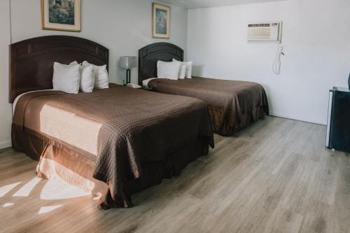 two beds in a hotel room with wooden floors at La Hacienda Motel in Seattle