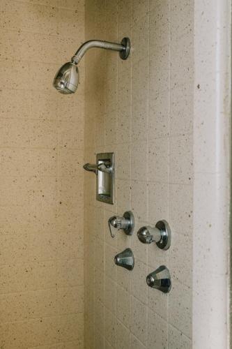 a shower with a shower head in a bathroom at La Hacienda Motel in Seattle