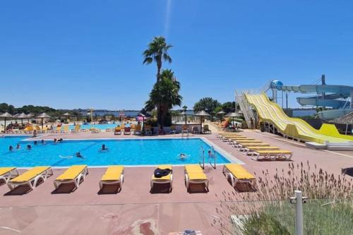 a pool with chairs and a slide at a resort at Mobile Home 450 4-6 pers Camping Siblu Le Lac des Rêves in Lattes