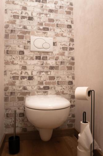 La salle de bains est pourvue de toilettes blanches et d'un mur en briques. dans l'établissement Duplex LE STUD'71 - 100m de la gare, à Chalon-sur-Saône