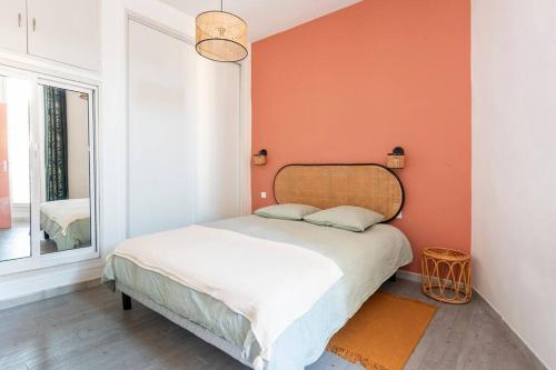 une chambre avec un lit avec un mur orange dans l'établissement Appartement Endoume, à Marseille