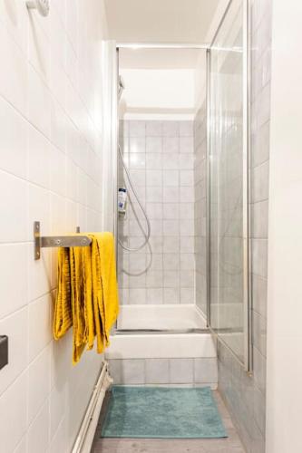 La salle de bains est pourvue d'une douche et de serviettes jaunes. dans l'établissement Appartement Endoume, à Marseille
