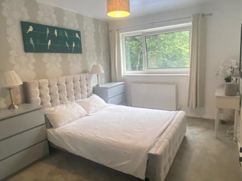 a bedroom with a white bed and a window at Beautiful 3 Bedroom Home in St Albans in Saint Albans