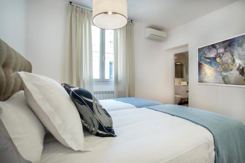 een slaapkamer met een bed met witte lakens en kussens bij Slow Suites Augusto in Madrid