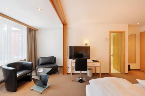 Habitación de hotel con cama, silla y escritorio. en Hotel Dischma en Davos