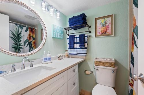 a bathroom with a sink and a toilet and a mirror at "Summer Winds" at Sunglow Resorts with Spectacular Ocean Views in Daytona Beach Shores