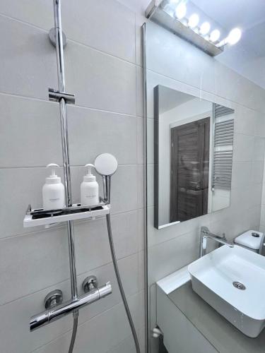 a white bathroom with a sink and a mirror at Nubia Modern Apartment in Craiova