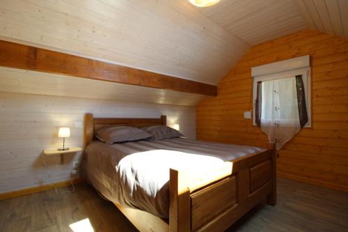 une chambre avec un lit dans une cabane en bois dans l'établissement Gîte à Rufus, Maison de charme au Ménil, au cœur de la nature vosgienne, à Le Ménil