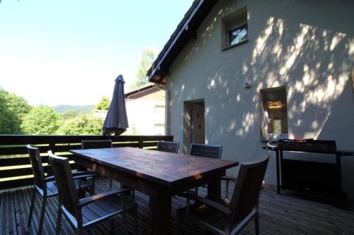 une table et des chaises en bois sur une terrasse dans l'établissement Gîte à Rufus, Maison de charme au Ménil, au cœur de la nature vosgienne, à Le Ménil