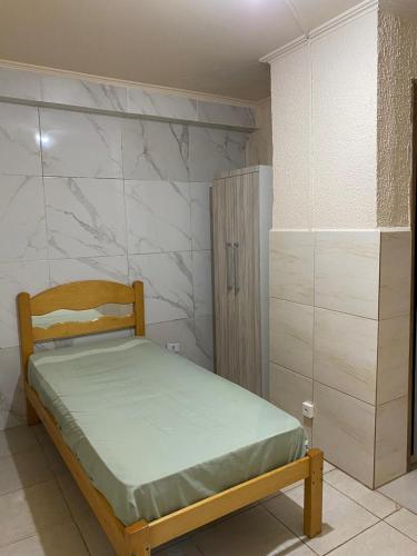 a small bedroom with a bed and a cabinet at Hospedagem e kitnetes D' Itália in Curitiba