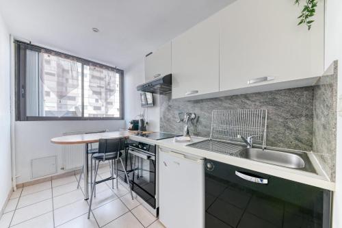 a kitchen with white cabinets and a sink and a counter at Charming Flat in Villeurbanne Gratte-Ciel in Villeurbanne