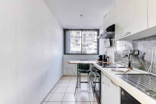 a white kitchen with a counter and a table at Charming Flat in Villeurbanne Gratte-Ciel in Villeurbanne